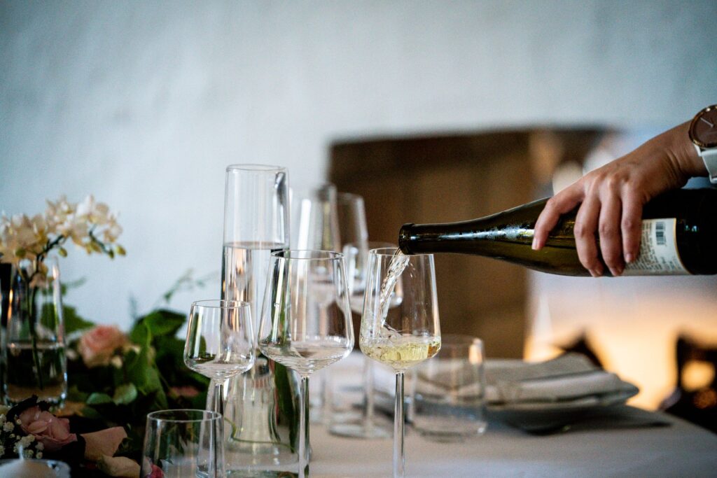 White wine being poured into elegant glasses at a dinner table setting