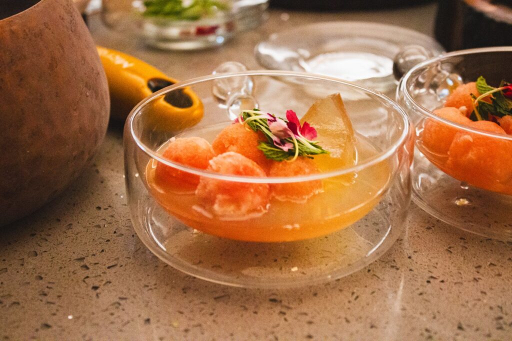 Elegant glass bowls of citrus sorbet garnished with fresh mint and an edible flower, served as a palate-cleansing intermezzo between savory and sweet courses