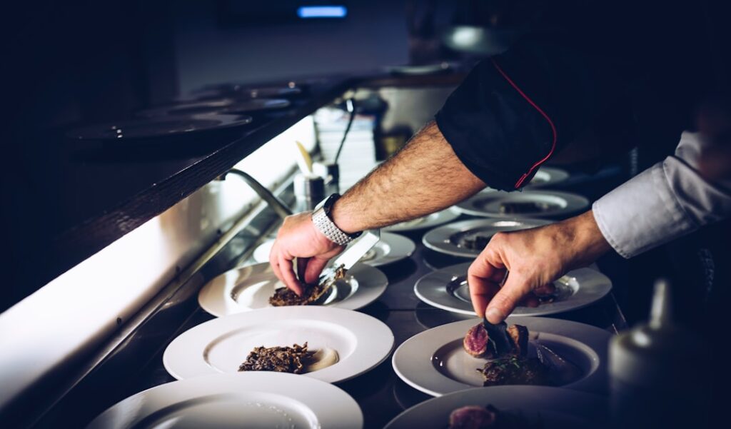 A chef in a professional kitchen meticulously plates multiple dishes simultaneously, demonstrating the precision and consistency Michelin inspectors evaluate.