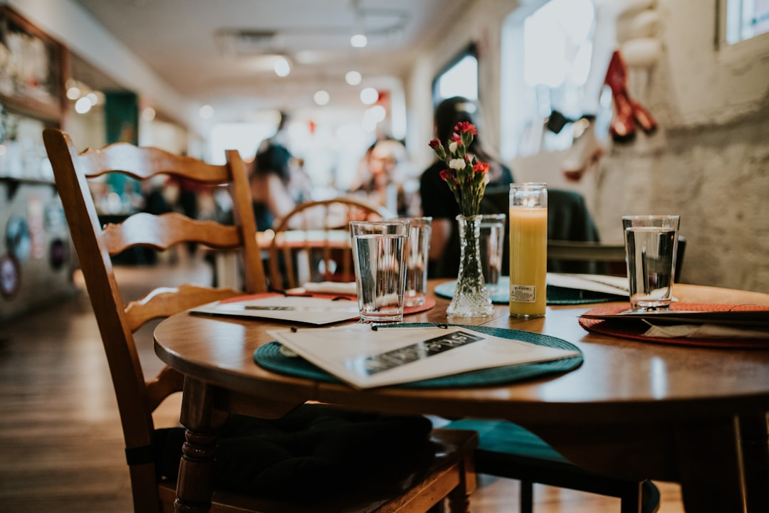 Casual restaurant dining table set with menus, glasses, and a small vase of flowers in a warm, inviting room