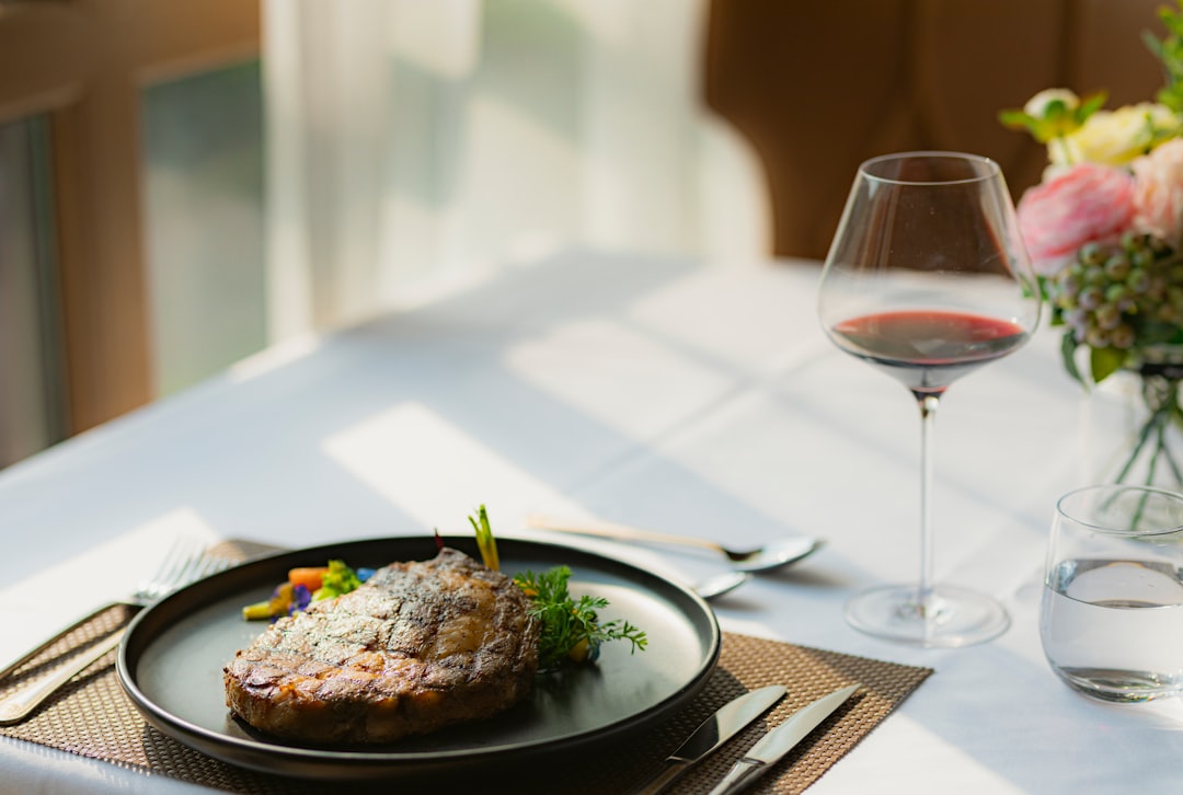 A beautifully plated steak with a glass of red wine on a restaurant table, illustrating steak and wine pairing