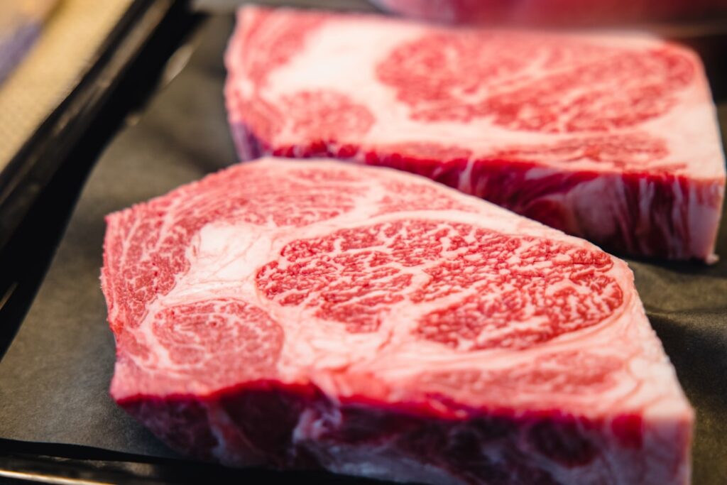 Heavily marbled ribeye steaks showing intramuscular fat that softens tannins in red wine pairings